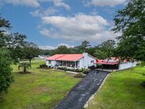 Charming single-story home boasts a red roof, a well-manicured lawn, and a long asphalt driveway at 274 Harvest Rd, Moncks Corner, SC 29461