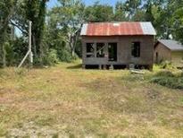 Exterior home view showing a small structure with a rusted metal roof and a large yard at 305 E 1St N St, Summerville, SC 29483