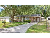 Charming brick home with green shutters, a well-manicured lawn, and a long concrete driveway at 4767 June St, North Charleston, SC 29405