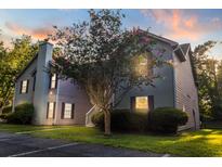 Charming condo featuring mature landscaping, a chimney, and beautiful sunset lighting at 7950 Parklane Ct # C, North Charleston, SC 29418