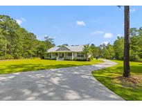 Inviting ranch-style home with a long driveway and lush green lawn surrounded by mature trees at 110 Huntington Ct, Walterboro, SC 29488