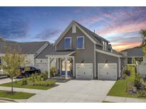 Beautiful two-story gray home with blue shutters, a welcoming porch, and a two-car garage at 110 True Blue Lp, Summerville, SC 29486