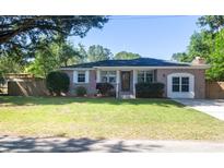 Charming brick home with well-maintained lawn, mature trees, and an American flag at 1261 Hampshire Rd, Charleston, SC 29412