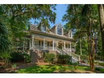 Charming home featuring a covered porch with white columns and stairs surrounded by lush greenery at 132 Turnberry Dr, Johns Island, SC 29455
