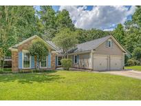 Charming brick and siding home featuring a well-manicured lawn, blue shutters, and a two-car garage at 138 Wainwright Manor, Summerville, SC 29485