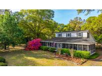 Charming two-story home featuring a screened porch, complemented by vibrant azaleas and lush landscaping at 1518 Southwick Dr, Johns Island, SC 29455