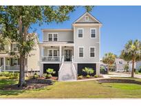 Charming gray two-story home boasts inviting front porch, manicured lawn, and lush landscaping on a sunny day at 1536 Keshi Pearl Dr, Mount Pleasant, SC 29466