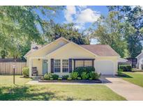 Charming yellow home with landscaped yard, inviting front porch, and attached garage offers great curb appeal at 2076 Presidio Dr, Mount Pleasant, SC 29466