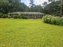 Single story brick home featuring a lush lawn with mature landscaping, trees, and a covered entry at 8719 Jefferies Hwy, Walterboro, SC 29488