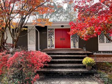 Charming home featuring a bold red front door, unique architectural details, and beautifully landscaped front entrance at 2535 Fairfax Dr, Gastonia, NC 28054