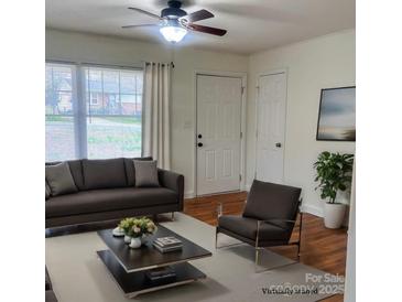 Virtually staged living room featuring hardwood floors, comfy seating, and large windows at 3918 Barlowe Rd, Charlotte, NC 28208