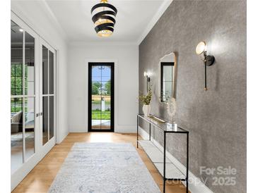 Elegant foyer with stylish lighting, decorative mirror, console table, and view of the outdoors through a black framed door at 4142 Pineview Rd, Charlotte, NC 28211