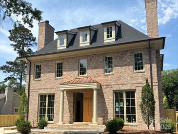 Stunning brick two-story home featuring a welcoming portico entry and symmetrical window design, complete with manicured landscaping at 1969 Maryland Ave, Charlotte, NC 28209
