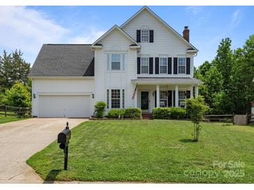 Charming two-story home features a well-manicured lawn, a classic white exterior, and inviting front porch at 5535 Whispering Wind Ln, Indian Trail, NC 28079