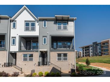 Modern townhome with gray siding, brick accents, black trim, balcony, and well-manicured landscaping at 320 Ferebee Pl # Brx0021, Charlotte, NC 28213