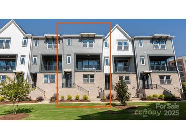View of the townhome exterior with gray siding, brick accents, and a small front yard at 312 Ferebee Pl # Brx0023, Charlotte, NC 28213