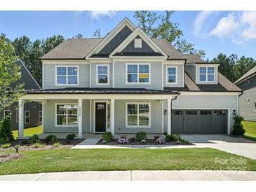 Charming two-story home featuring a covered front porch, manicured lawn, and attached two-car garage at 2016 Cedar Falls Dr # 7, Waxhaw, NC 28173