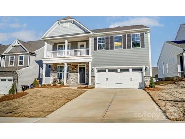 Charming two-story home featuring a stone-accented facade, a cozy front porch, and a convenient two-car garage at 130 Summerhill Dr # 16, Mooresville, NC 28115