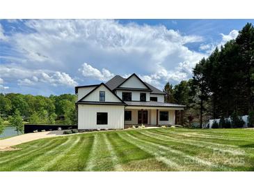 Beautiful modern farmhouse with manicured lawn, complemented by a picturesque sky and lush greenery at 110 Emmaline Ct, Troutman, NC 28166