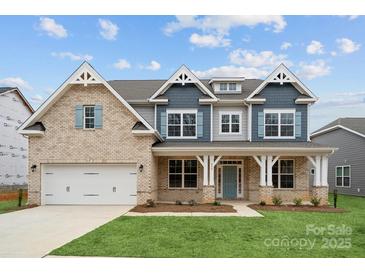 New two-story home boasts a brick facade, blue accents, an attached two-car garage, and a well-manicured front lawn at 232 E Warfield Dr, Mooresville, NC 28115