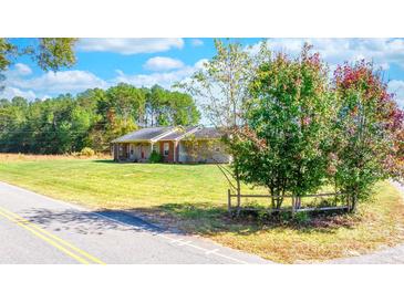 Ranch home with brick and siding, spacious lawn, and a partially visible country road at 927 Happy Plains Rd, Taylorsville, NC 28681