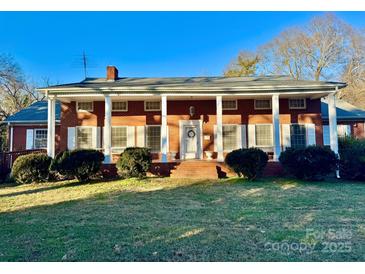 Brick house with a large front porch and mature landscaping at 1506 Dallas Cherryville Hwy, Dallas, NC 28034