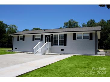 Newly renovated ranch home featuring a gray brick exterior, black shutters, and a spacious driveway at 4230 Northaven Dr, Charlotte, NC 28206