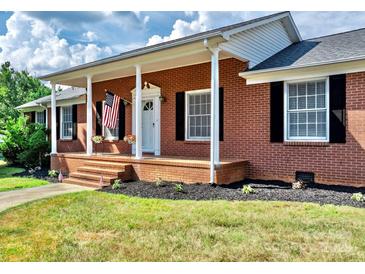 Brick home with a large front porch and American flag at 2909 Eastway Dr, Statesville, NC 28625