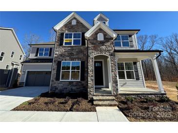 Two-story home with stone and siding accents, a front porch, and a two-car garage at 5031 Mclaughlin Loop # 60, Waxhaw, NC 28173