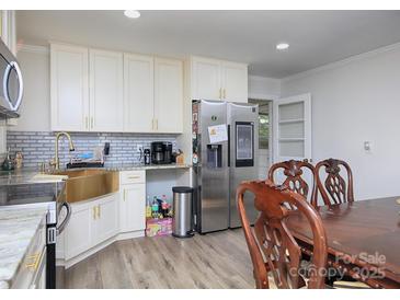 Bright kitchen with white cabinetry, stainless steel appliances, gold accents and a bronze sink at 3119 Hickory Hwy, Statesville, NC 28677