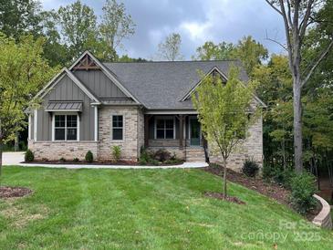 Charming stone and siding home with a well-manicured lawn and mature trees under cloudy skies at 859 Tamary Way # 34, Landis, NC 28088