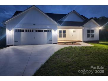 Charming single-story home with a two-car garage, manicured lawn, and modern white siding at 9609 Stokes Ferry Rd, Gold Hill, NC 28071