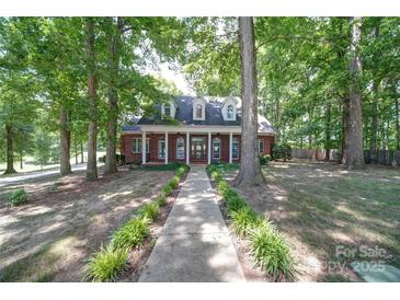 Charming brick home featuring a welcoming front porch, dormer windows, and a meticulously landscaped yard at 3814 Watson Church Rd, Monroe, NC 28110