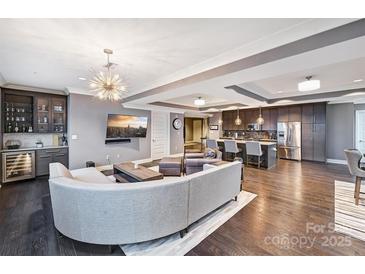 Open concept living room flows to a modern kitchen with stainless steel appliances and dark wood floors at 222 S Caldwell St # 2007, Charlotte, NC 28202