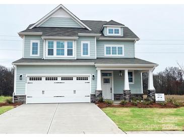 Charming two-story home with attached garage, front porch, stone accents, and manicured lawn at 4808 Glen Stripe Dr # Cal0036, Indian Trail, NC 28079