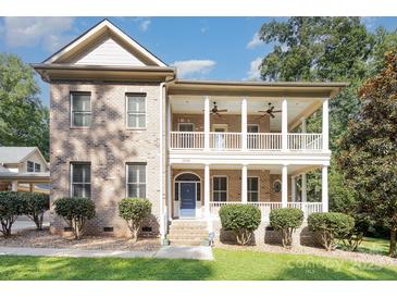 Charming brick home with a welcoming double-decker front porch and manicured landscaping at 5888 Hidden Oaks Ln, Clover, SC 29710