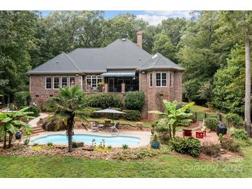 Stunning backyard features a brick home, pool, and beautiful landscaping for ultimate outdoor relaxation at 4364 Hager Mountain Ln, Iron Station, NC 28080