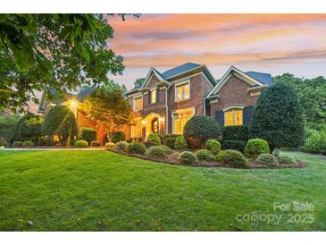 Brick home with manicured landscaping and nighttime lighting at 7025 Willow Trace Ln, Weddington, NC 28104