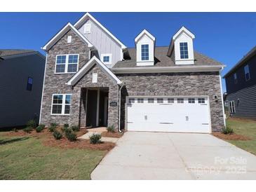 Two-story house with stone exterior, white garage door, and landscaping at 10108 Whitaker Pointe Dr, Huntersville, NC 28078