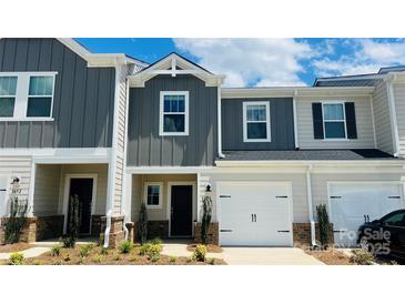 Charming townhome featuring a two-car garage and modern gray and beige siding at 1650 Village Grove Ln, Monroe, NC 28110