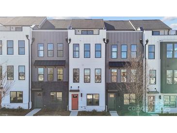 A modern townhouse featuring a combination of white and gray siding, black brick, and a vibrant red front door at 455 Blairhill Rd # 03, Charlotte, NC 28217