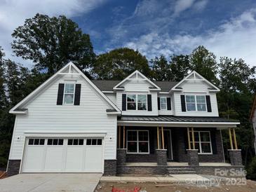 Two story home with white siding, gray stone accents, and a three-car garage at 3245 Mcharney Dr # 28, Harrisburg, NC 28075