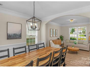 Bright dining room features a large wooden table with seating for eight at 11407 Sidney Crest Ave, Charlotte, NC 28213