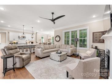 Spacious living room with hardwood floors, large sectional sofa, and open floor plan to kitchen and dining at 859 Irish Creek Dr, Landis, NC 28088