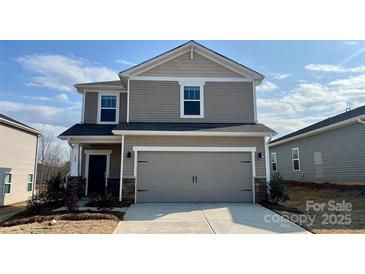 Two-story home featuring tan siding, stone accents, a two-car garage, and well-manicured landscaping at 158 Shepherds Landing Dr, Mooresville, NC 28115