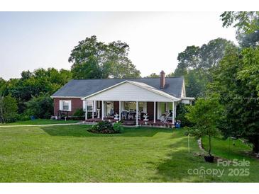 Charming brick home featuring a welcoming front porch and beautifully maintained lawn and landscaping at 3021 Davis Park Rd, Gastonia, NC 28052