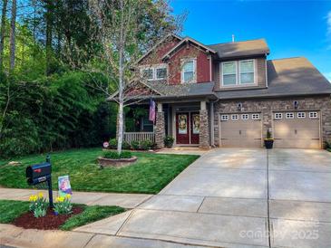 Two-story house with stone and red siding, two-car garage, and landscaped yard at 12528 Generations St, Charlotte, NC 28278