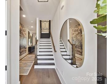 Inviting entryway with hardwood floors, statement mirror, and staircase with wooden handrail at 3020 Endhaven Terraces Ln # 10, Charlotte, NC 28277