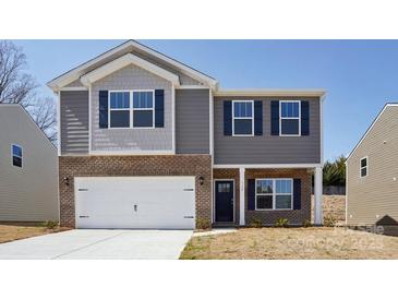 Charming two-story home featuring a brick and gray siding exterior, complemented by a two-car garage and a neatly manicured lawn at 112 Rustling Waters Dr, Mooresville, NC 28117