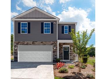 Two-story home with gray siding, stone accents, and a white garage door at 5211 Reedy Ridge Rd, Charlotte, NC 28215